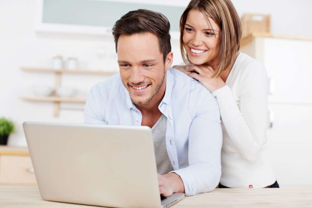 Laughing couple browsing the internet at the laptop