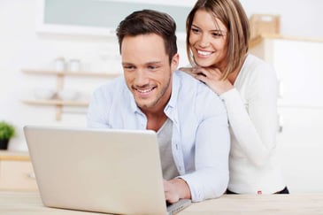 smiling couple browsing the internet on a laptop