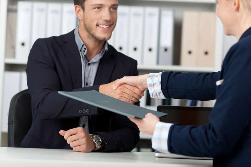 Happy businessman shaking hands with a female interviewer in office